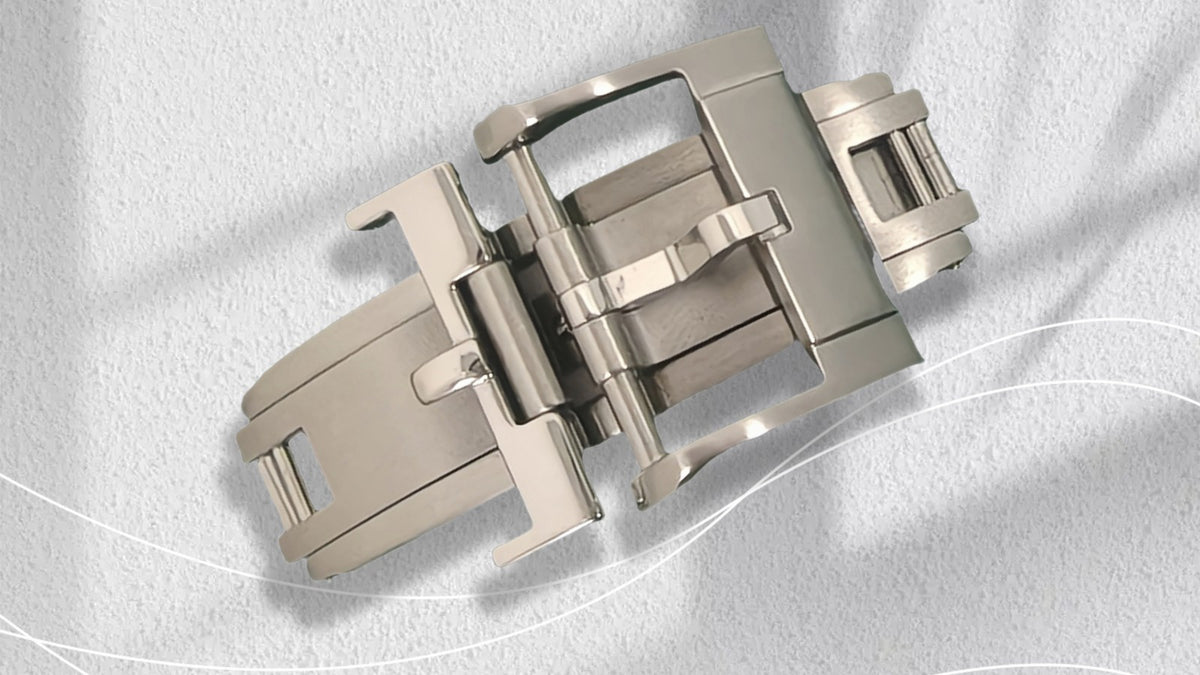 Stainless steel butterfly deployant clasp photographed on a white surface
