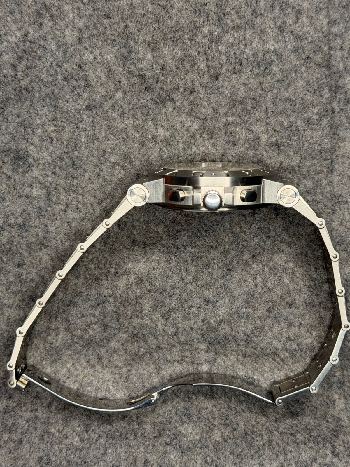 Side profile showing the chronograph pushers, fluted crown and integrated stainless steel bracelet