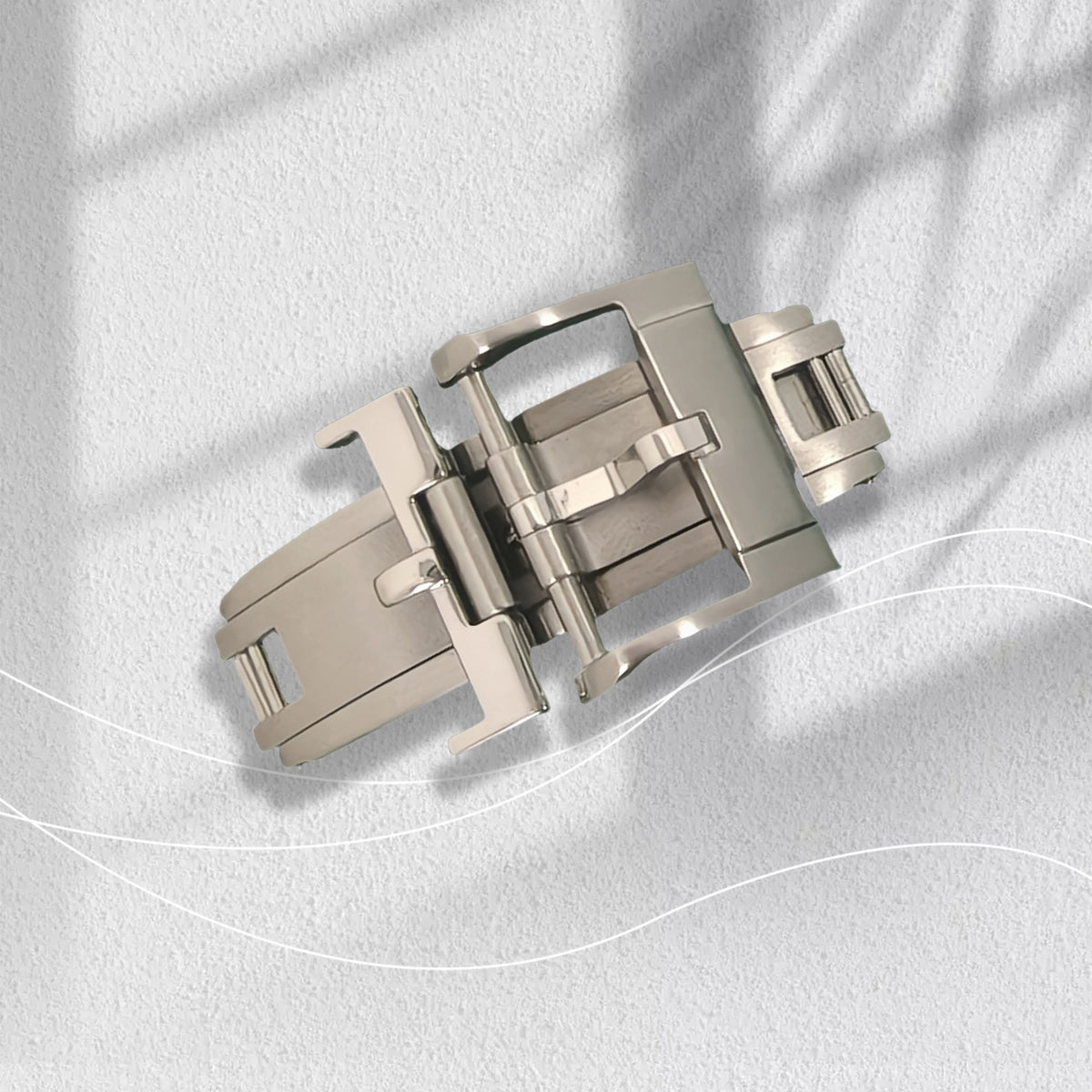 Stainless steel spring deployant butterfly clasp, open, on a white surface
