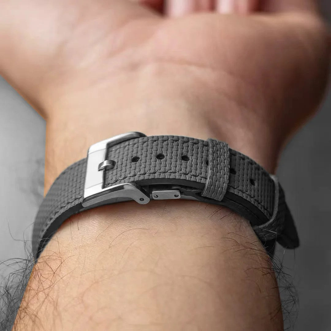Deployant clasp fastened on a grey textile watch strap worn on the wrist