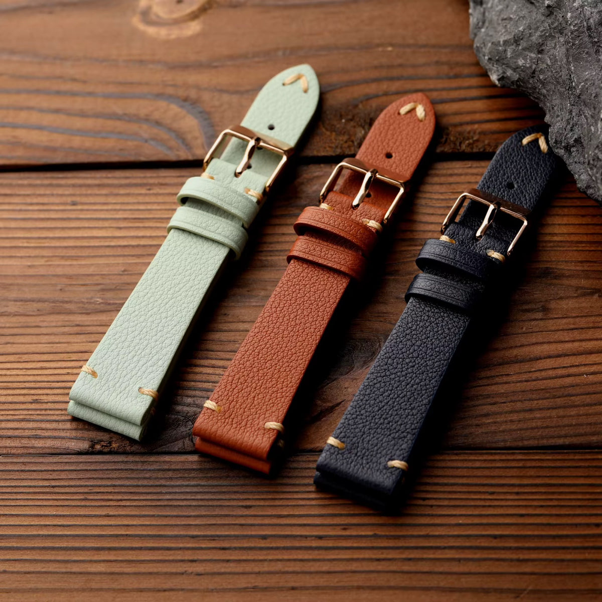 Seven-colour French goat leather watch straps in sage green, cognac and navy on wood