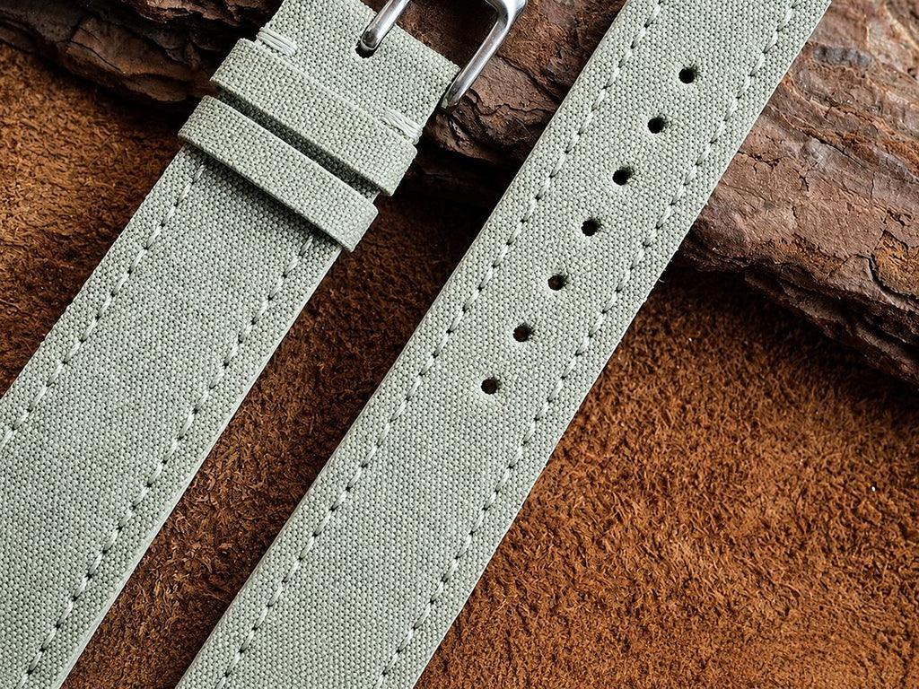 Close-up of sage green sailcloth watch strap stitching and quick-release buckle
