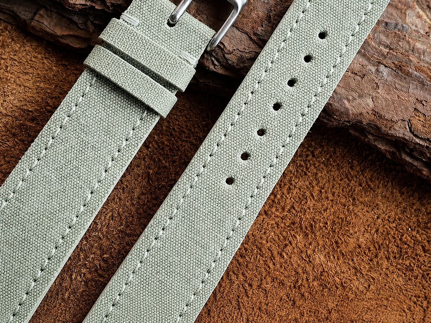 Close-up of sage green sailcloth watch strap stitching and quick-release buckle