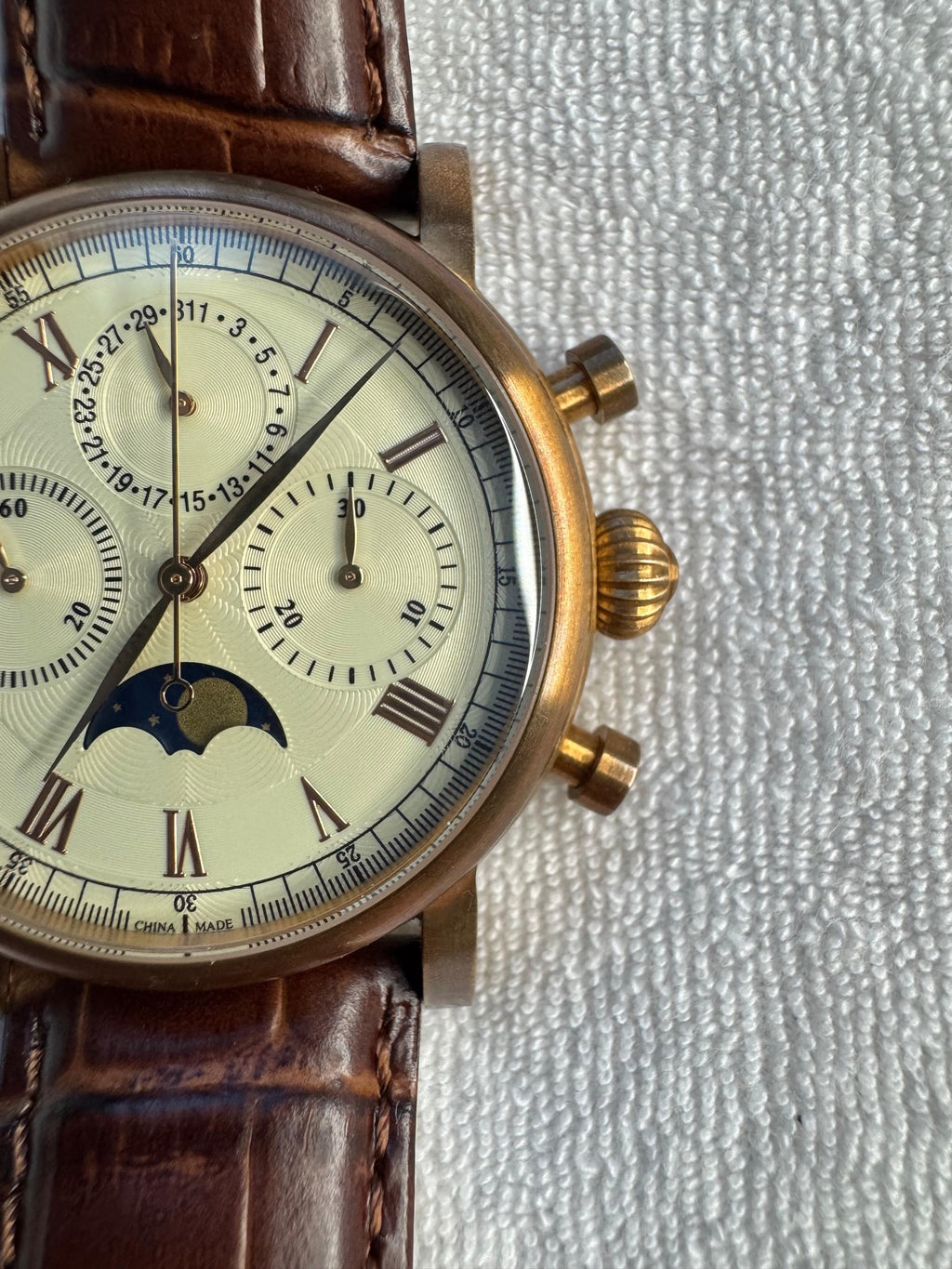 Close-up of the cream guilloche dial, onion crown and chronograph pushers on the bronze-tone Sea-Gull case