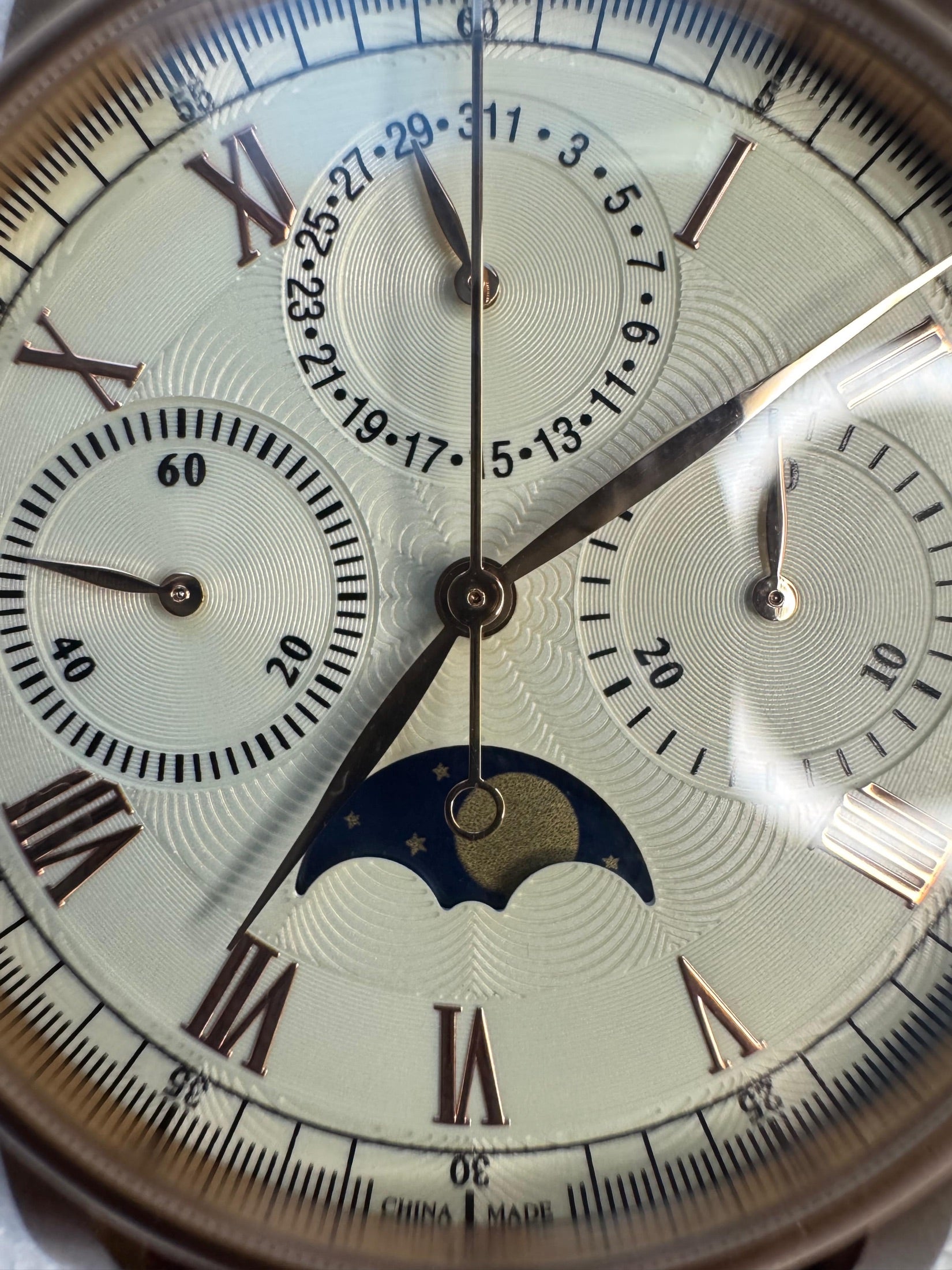 Macro of the dial showing the blue moon phase aperture, pointer date, small seconds and 30-minute chronograph counter