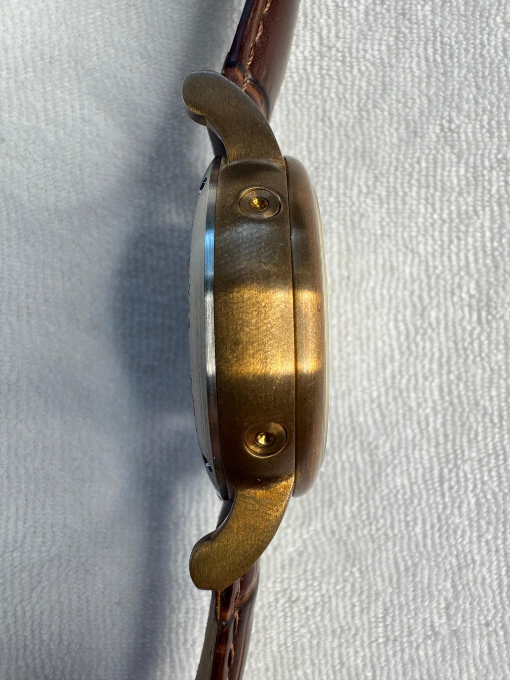 Side profile of the bronze-tone case showing teardrop lugs, domed crystal and chronograph pushers